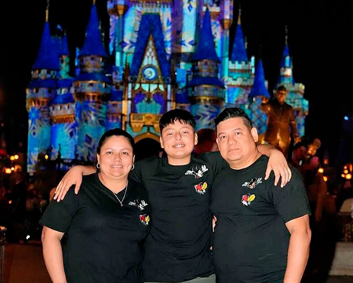 Familia posando frente al Castillo de Cenicienta iluminado de noche en Magic Kingdom, Walt Disney World.