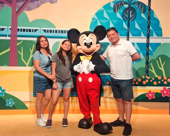 Familia posando con Mickey Mouse en un área temática interior de Disney.