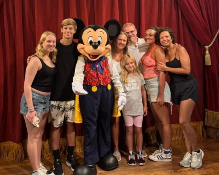 Grupo familiar posando con Mickey Mouse en un encuentro con personajes de Disney.