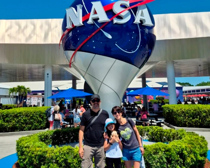 Familia posando frente al ícono de la NASA en el Kennedy Space Center Visitor Complex.