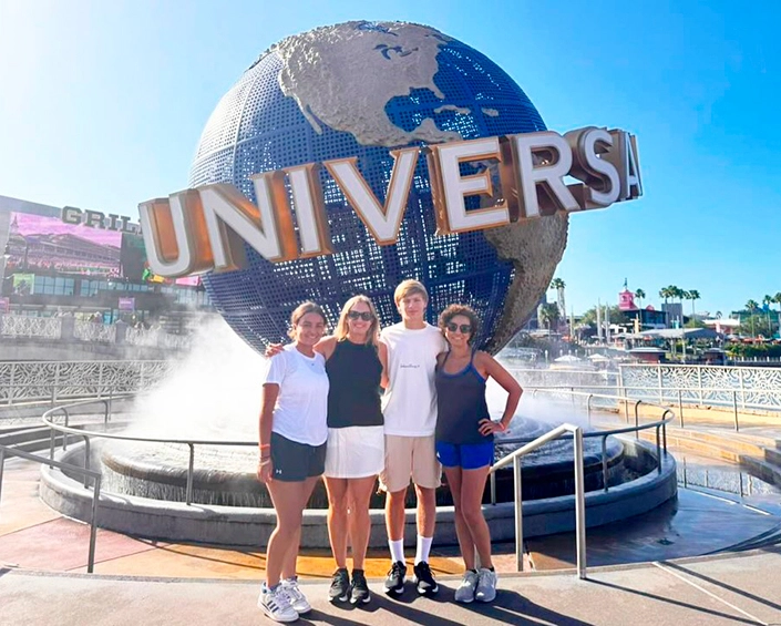 Grupo de visitantes posando frente al globo de Universal Studios bajo cielo despejado.