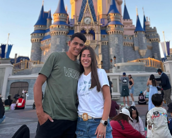 Pareja joven posando frente al Castillo de Cenicienta en Magic Kingdom al atardecer.